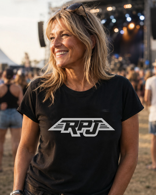 A woman smiling outdoors at a festival or concert, wearing a black short-sleeve T-shirt with a large white stylized 'RPJ' logo across the chest.

